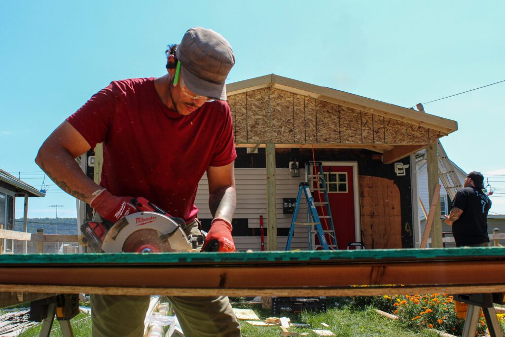 Construction worker cutting wood as part of commercial exterior fit-out services, including decks, patios, garages, storage and outbuildings, and outdoor gathering spaces.