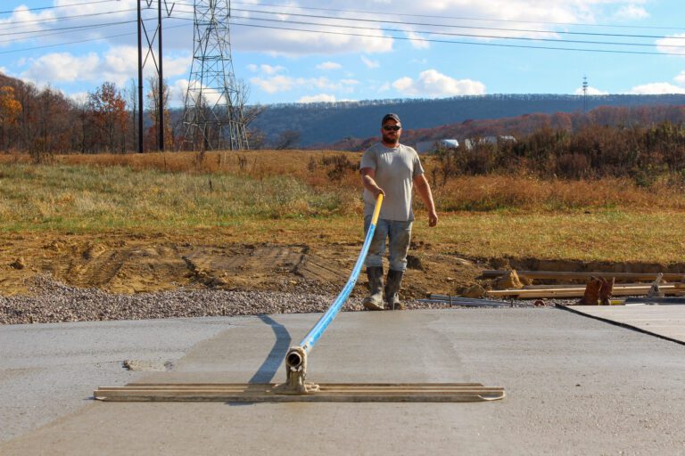 Construction services shown by a professional cement finisher using a tool on a driveway job, demonstrating expert craftsmanship and precision.