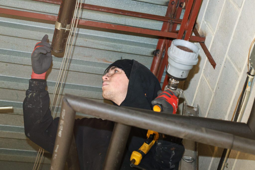 A plumber installs piping in a commercial building, demonstrating integrated design build services for plumbing and infrastructure.