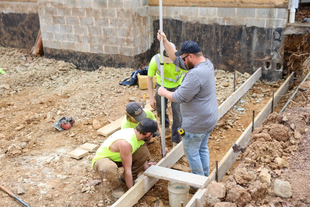 A crew of professional Goodridge Construction workers preparing a house foundation as part of residential real estate developers layout, including expert land preparation and excavation services.