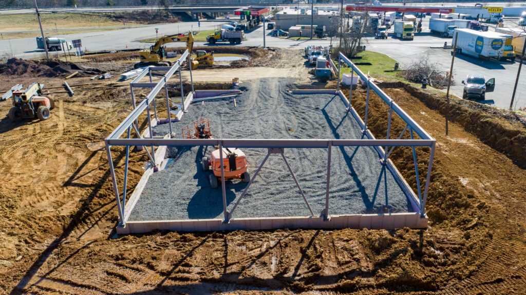 Aerial view of a commercial site under construction, showcasing coordinated design build services across all trades and phases.