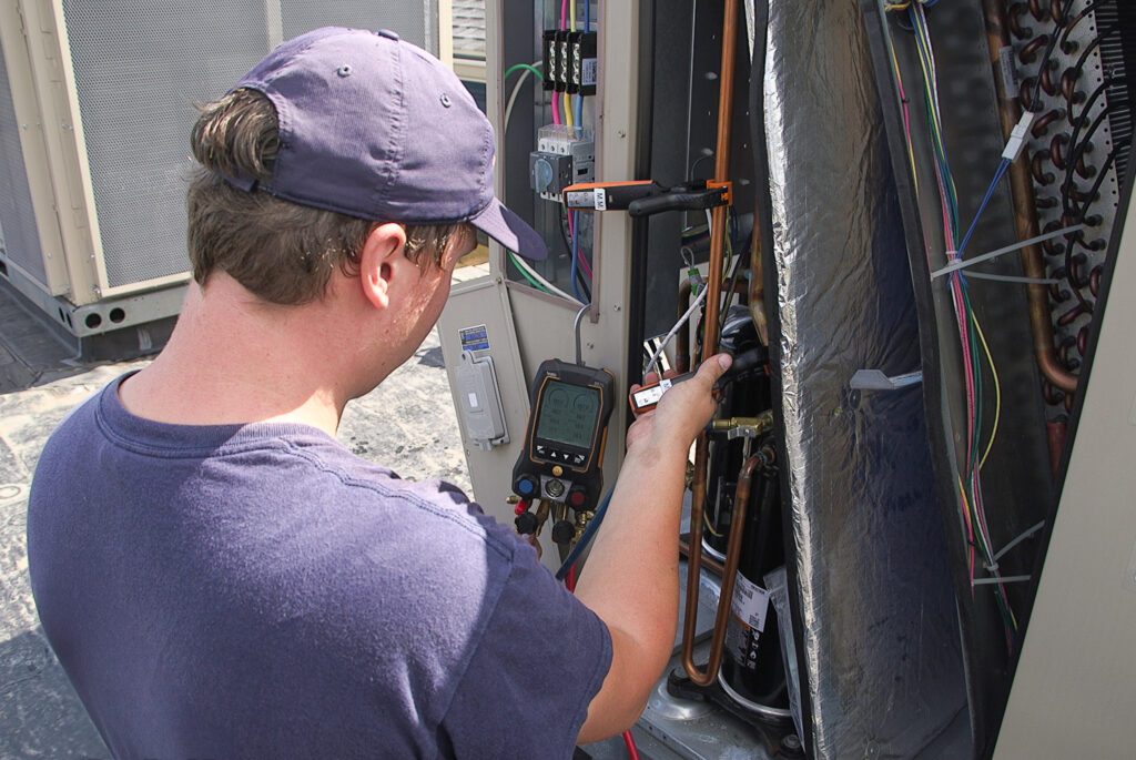 A professional HVAC technician installing a new system component demonstrates comprehensive Residential HVAC Inspection Services, including HVAC system inspections and air quality & ventilation assessment, ensuring energy-efficient, reliable, and fully operational commercial spaces.