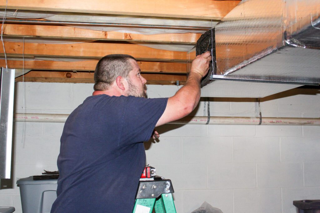 Residential Humidity Control Services being performed by a professional Goodridge Construction HVAC tech installing heating and cooling vents for balanced airflow, supporting whole home dehumidifiers and complete HVAC system optimization.