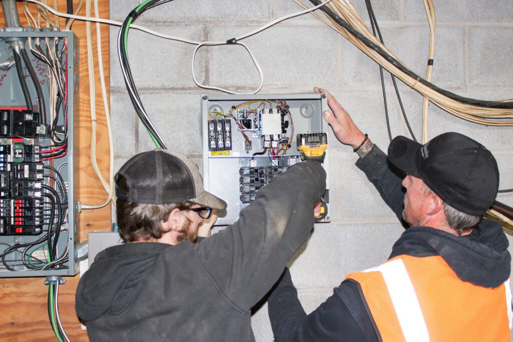 Two electricians installing a breaker box delivering electric services and smart home system installation as part of residential electrical system design and circuit breaker panel upgrades in NEPA