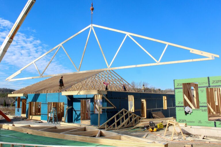 A crane lowers roof trusses on a framing project, highlighting expert craftsmanship in new construction services, home addition services, and garage construction services.