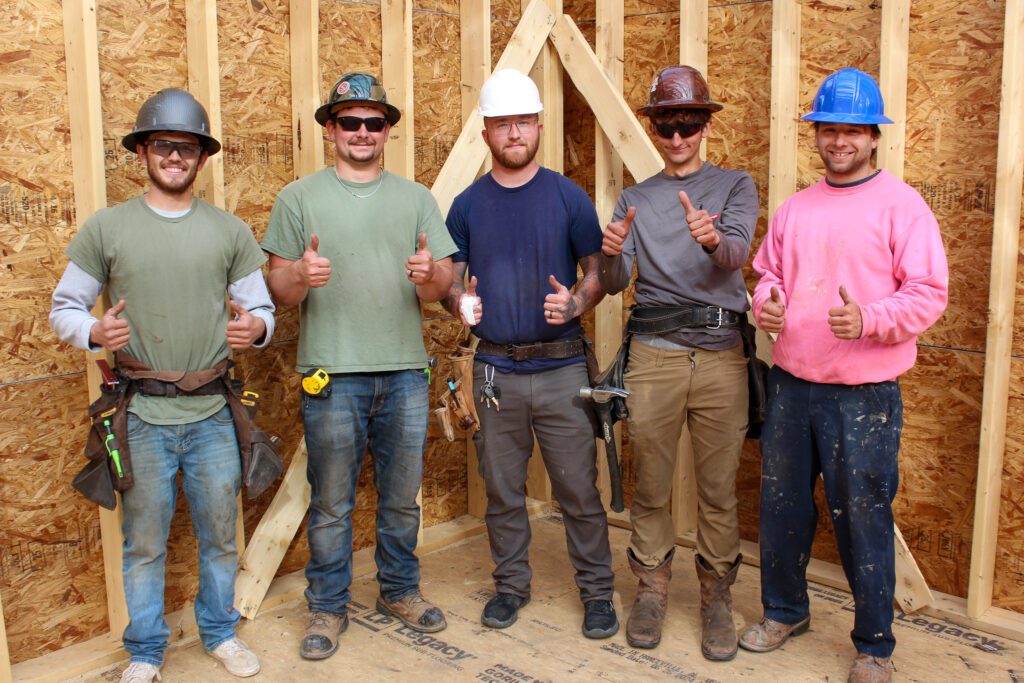 "Construction crew celebrating completion of commercial new construction framework, demonstrating teamwork and expertise in commercial new construction services and design-build services."