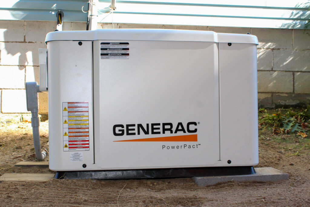 A licensed electrician installing a commercial generator beside a facility, showing wiring setup and safety equipment as part of Power Factor Correction Solutions to improve energy performance and reliability.