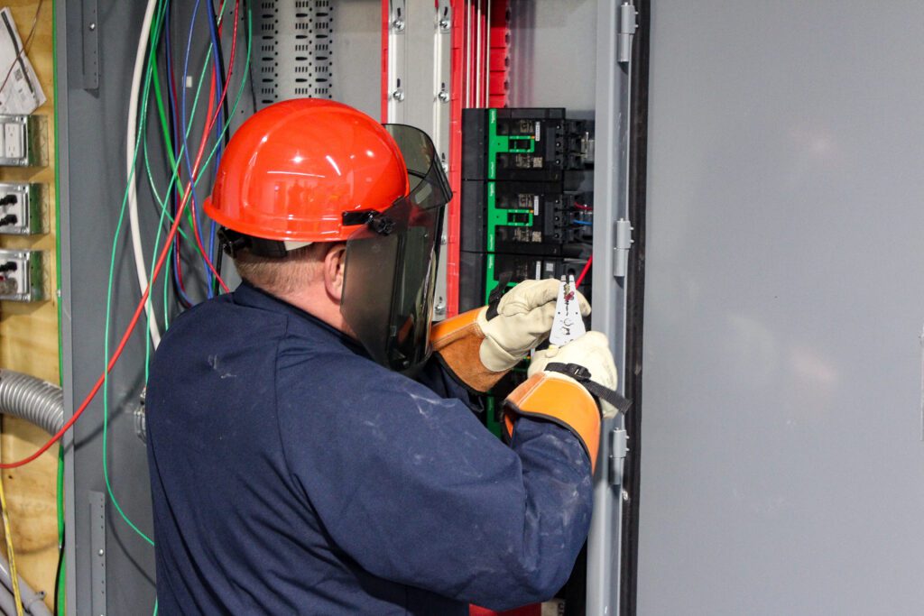 A licensed electrician works on a commercial breaker box, demonstrating expert general construction practices for safe and efficient electrical systems.