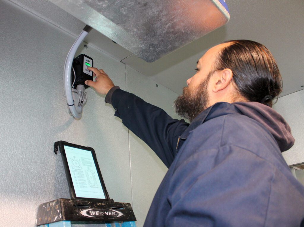 Professional HVAC technician servicing a large commercial freezer unit as part of commercial refrigeration services, ensuring safe cooling performance and reliable system operation.