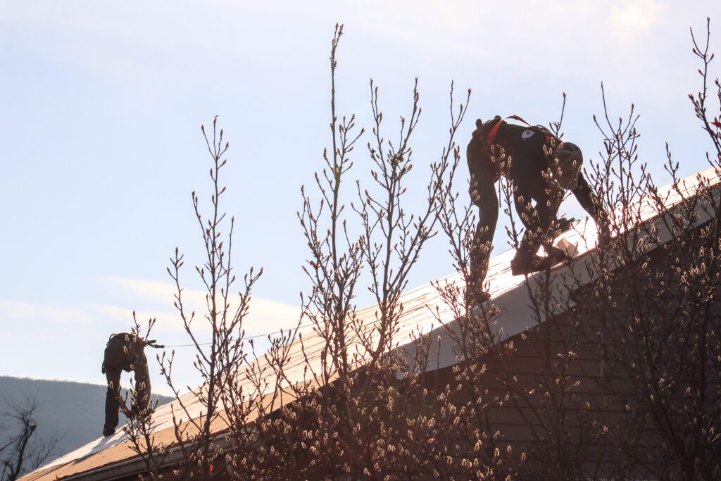 Two roofing professionals install materials on a commercial building, illustrating expert general construction for durable roofing solutions.